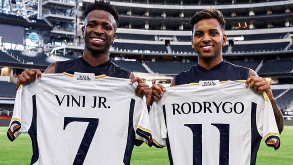 Vinícius Jr ao lado de Rodrygo, ambos segurando suas camisas do Real Madrid